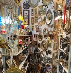 a room filled with lots of different types of framed pictures and mirrors on the wall