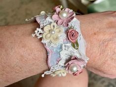 a close up of a person's arm wearing a bracelet with flowers on it