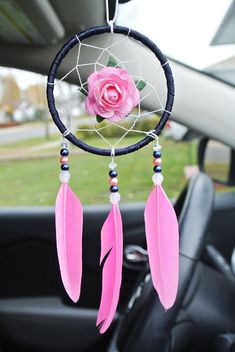 a car dashboard with a pink rose hanging from it's center console and a black dream catcher