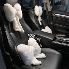 two stuffed animals sitting on the front seats of a car with matching headrests