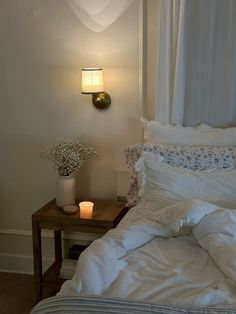 a bed with white sheets and pillows next to a night stand