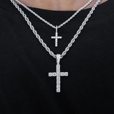 a man wearing a black shirt and two silver chains with a cross on the front