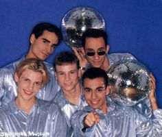 a group of young men standing next to each other in front of a mirror ball