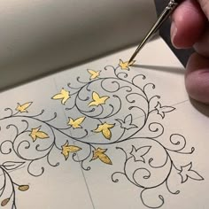 someone is drawing something with yellow butterflies on white paper and using a pen to draw it