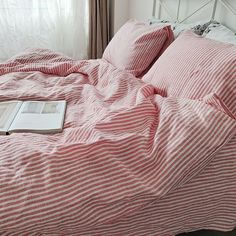 a bed with red and white striped comforter next to a book on top of it