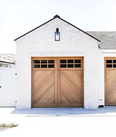 two brown garage doors are open in front of a white house