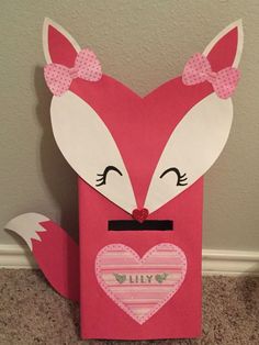 a paper bag with a fox face and pink bow on the front, sitting on carpet