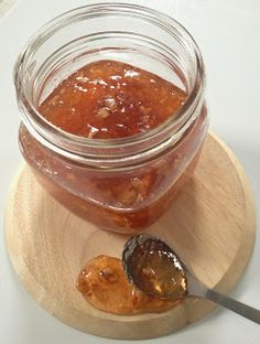 a jar filled with jam sitting on top of a wooden plate next to a spoon