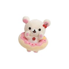 a small white teddy bear sitting on top of a donut with pink frosting