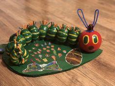 the very colorful caterpillar is next to an apple on a green plate with magnets