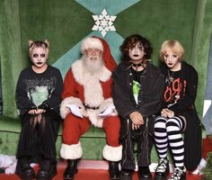 three children and an adult sitting on a bench dressed up as santa claus with other kids