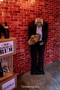 a statue of a man holding a plate in front of a brick wall with the words old american drum written on it