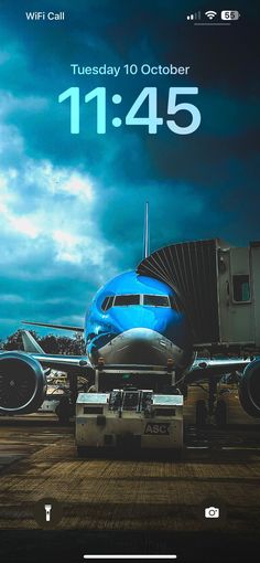 an airplane sitting on the tarmac next to a blue sky with clouds in the background