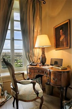 an old fashioned desk and chair in front of a window with a painting on the wall