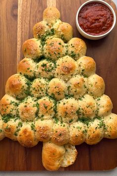 a christmas tree made out of rolls on a cutting board next to a bowl of ketchup