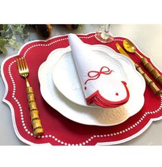 a red and white placemat with a horse on it, next to gold utensils