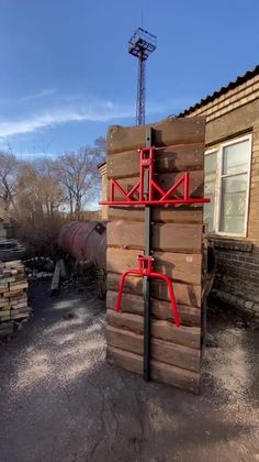 a red metal object sitting on top of a pile of wooden pallets in front of a building