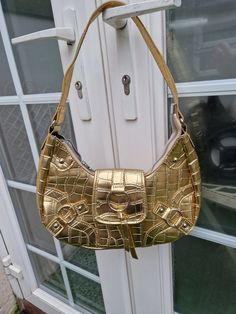 "Unusual bright gold lightweight moon shaped bag with zipped top and popper clasp, y2k era Synthetic pu material, with all over mock crog design Can be mini shoulder bag or carried by handle Very good condition Great party statement bag  Measurements: inches 11\" wide 5.5\" deep 3\" base strap measures 16.5\" All orders are shipped using biodegradable and recycled packaging where possible" Gold Bucket Shoulder Bag With Gold-tone Hardware, Gold Rectangular Shoulder Bag With Zipper Closure, Gold Shoulder Bag With Gold-tone Hardware, Gold Shoulder Bag With Metal Hardware, Gold Rectangular Shoulder Bag With Zipper, Trendy Gold Shoulder Bag, Gold Handheld Shoulder Bag With Zipper Closure, Gold Shoulder Bag With Zipper For Daily Use, Handheld Gold Shoulder Bag With Zipper Closure