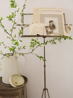 there is a vase with flowers in it next to an old fashioned photo frame on a stand