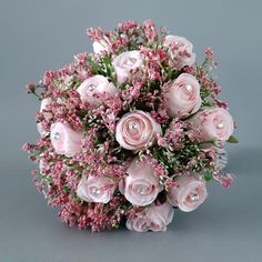 a bouquet of pink roses and baby's breath on a gray background with pearls