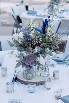 a vase filled with flowers sitting on top of a white table covered in blue napkins