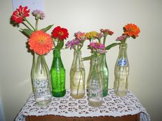 four vases with flowers are sitting on a table top in front of a wall