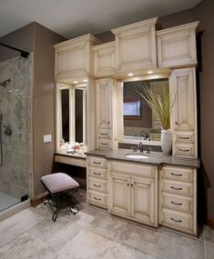 a large bathroom with white cabinets and marble counter tops, along with a walk in shower