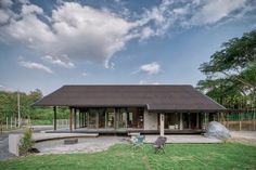 a house that is in the middle of some grass and has a lawn chair on it