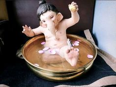 an elephant statue sitting on top of a bath tub filled with water and pink pebbles