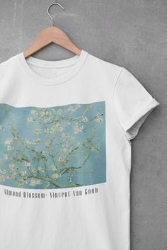 a white t - shirt with an almond blossoming tree on the front and blue sky in the back