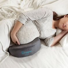 a pregnant woman laying on top of a bed next to a pillow that is shaped like an ostrich