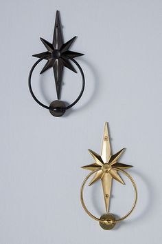 two black and gold metal objects on a white surface, one with a star design