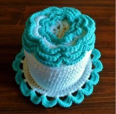 three crocheted hats are stacked on top of each other, one is blue and the other is white