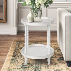 a living room with a couch, coffee table and flower arrangement on the end table