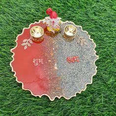 a decorative tray on the grass with two cups and saucers in front of it