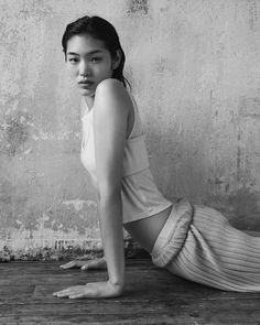 black and white photograph of a woman sitting on the floor in front of a wall