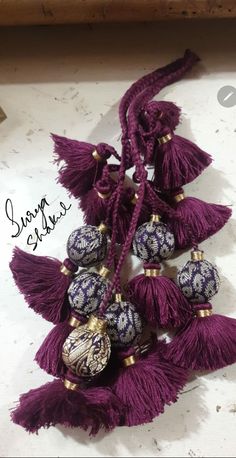 some tassels are laying on top of a white table and one is purple