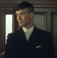 a man wearing a suit and tie standing in front of a door