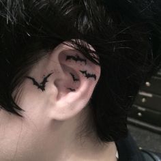 a person with black ink on their ears and behind the ear is a bat tattoo