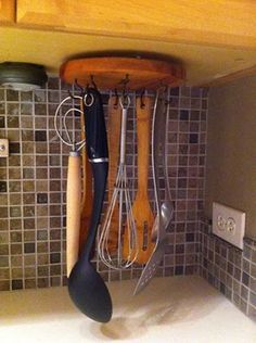 kitchen utensils hanging from the ceiling in a kitchen with tiled backsplash