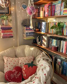 a chair with two pillows on it in front of a bookshelf full of books