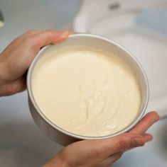 two hands holding a bowl of cream on top of a counter