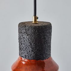 a black and red vase with a metal hook on it's end is shown