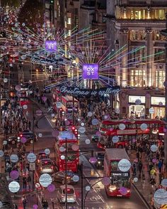 a busy city street at night with double decker buses and people walking on the sidewalk