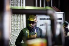 a man wearing a hat and holding a straw in front of a refrigerator freezer