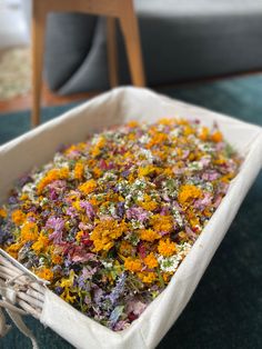 a white bowl filled with lots of flowers on top of a green tablecloth covered floor