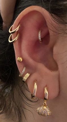 an ear with three different types of piercings on it's sides and one is gold