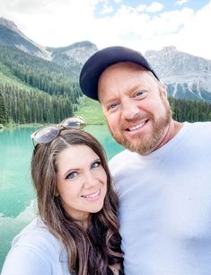 a man and woman taking a selfie in front of a mountain lake