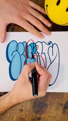 a person is drawing graffiti on a piece of paper with a marker and black pen