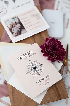 a passport sitting on top of a wooden table next to a purple flower